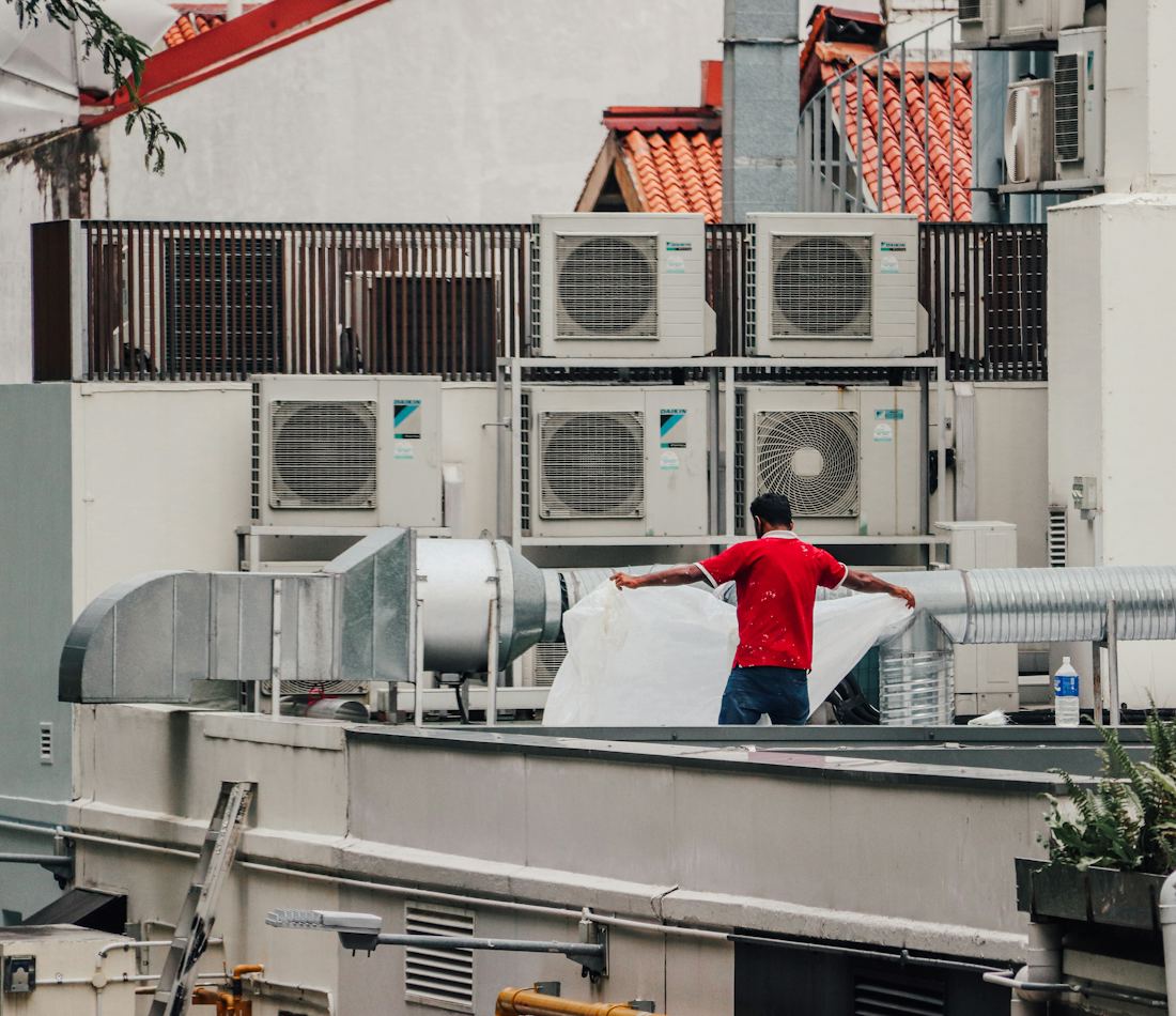 Teknisi sedang mengerjakan unit AC di area atap sebuah bangunan